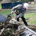 Lt. Gov. Phil Scott shovels debris into a bucket loader at a work site in Berlin's Weston Mobil Home Park. VTD/Josh Larkin
