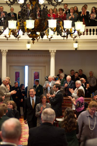 House representatives react as Gov. Peter Shumlin walks into the well of the Chamber.