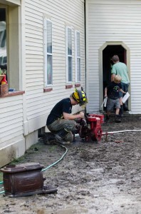 A Moretown fireman works on a pump as residents scramble to remove items from their home. VTD/Josh Larkin