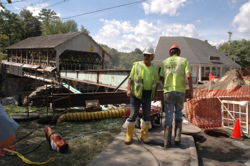 Workers for FairPoint stand by the road washout by the Quechee covered bridge, where crews worked to restore telephone, sewer, and water lines across the Ottauquechee River Wednesday. VTD/Andrew Nemethy