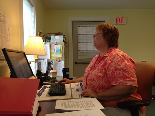 Cheryl Brown, administrative assistant for the Moretown Town Clerk's Office, works on the town’s latest Irene-related project in the temporary town office near the town landfill. Photo by John Herrick/VTDigger