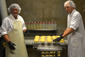 Stuart Gaboriault, left, and Tim Gifford apply a cider "wash" to the rind of some Winnimere cheese in a ripening cellar at Jasper Hill Farm. The 14 cheeses in the cellars  each have their own complex regimen and requirements for aging, which provides the flavor that can distinguish an award-winning cheese. Photo by Andrew Nemethy