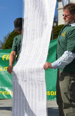 A petition with 1,200 signatures is held up at a rally organized by the Vermont State Employees Association, which represents some 250 Vermont State Colleges workers. Photo by Alicia Freese/VTDigger