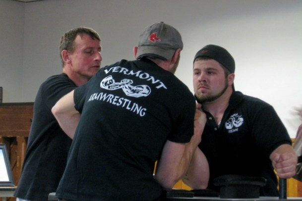 Referee Bill Sinks of Weybridge, left, one of the most renowned arm wrestlers in the world, wrestles with two pullers at the Dustin Mason Memorial Arm Wrestling tournament in Morrisville, to achieve the required grip to start the bout. Photo by Nancy Price Graff
