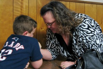 Theresa Howard of Wolcott, overall women's champion at the Mason Memorial Arm Wrestling Tournament, coaches her 7-year-old grandson, Shawn Bishop, before he heads to the table for his first contest. Photo by Nancy Graff