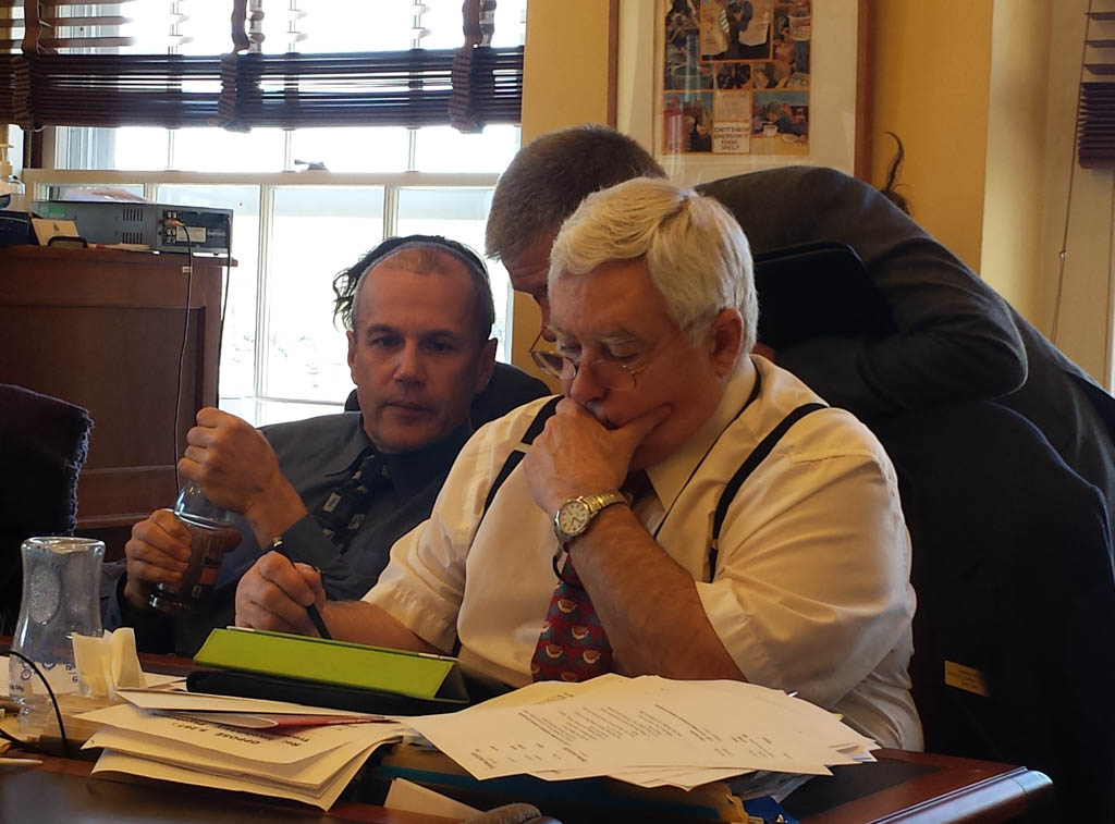 Department of Public Safety Commissioner Keith Flynn whispers to Rep. Tom Burditt (left), R-West Rutland, on how to amend S.247, a bill about medical marijuana. Rep. Topper McFaun, R-Barre Town, checks his iPad. Photo by Laura Krantz/VTDigger