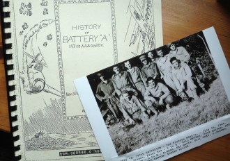 A 70-year-old photograph of Albert Sponheimer Jr. and his buddies during World War II, lies atop a history of his unit, Battery A of the 197th AntiAircraft Battalion.