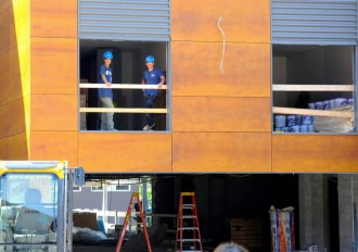 Workers look out the window of the new Hilton Garden hotel in Burlington, where a press conference on state tax credits was held Monday, Aug. 11, 2014. Photo by Hilary Niles/VTDigger.org