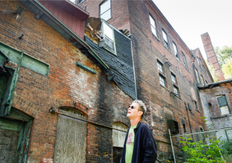 Painter Charlie Hunter examines the ruins of the massive Moore and Thompson Paper Mill Complex in Bellows Falls, which has been shuttered for nearly a century. Photo by Mark Bushnell