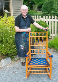 Warren Kimble displays “Spindle,” one of 30 rocking-chair works of art that were auctioned off last month by the Brandon Artists Gallery. The chair, which he painted with local artist Joan Drew, is “Syracuse orange,” the official colors of Kimble’s alma mater, Syracuse University. Photo by Dirk Van Susteren