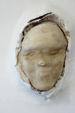 Riki Moss is still wrestling with how best to embed masks in walls. At the moment they are best compared to death masks, faces covered in abaca paper that clings like dry skin to the armature. Sunk in sheetrock and plaster, they emerge as unsettling and unsettled spirits from the netherworld. Photo by Nancy Graff