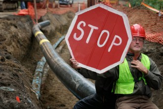 Raymond Micklon of Craftsbury Common and David Przepioski of Craftsbury Common locked their necks together in the 8-foot deep ditch to protest the Vermont Gas pipeline extension through Addison County. Photo by John Herrick/VTDigger