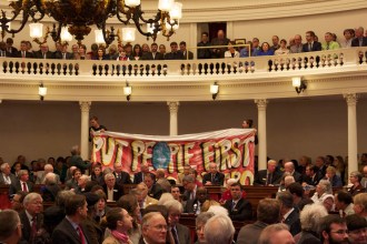 Demonstrators unfurl a banner in the House chamber Thursday, Jan. 8, 2015, as Gov. Peter Shumlin gives his inaugural address. Protesters packed the gallery demanding that Shumlin make good on his pledge to create a publicly financed health care system. Photo by John Herrick/VTDigger