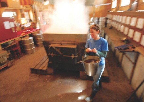 Rebecca Boucher carries syrup from the sap boiler to the filtering station at Nebraska Knoll Sugar Farm in Stowe earlier this month. Photo by Glenn Callahan/Stowe Reporter