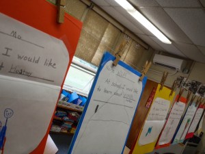 An internal unit of a new air-to-air heat pump system can be seen mounted on the wall behind students' work hanging in a classroom at NewBrook Elementary in Newfane. Photo by Mike Faher/VTDigger
