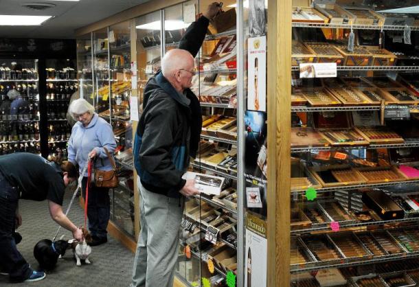 Bob Kruse of Bradford selects cigars  from the humidor at UnDun in West Lebanon, N.H. Photo by James M. Patterson/Valley News 