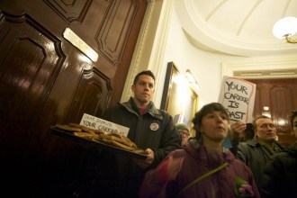 James Haslam, executive director of the Vermont Workers Center, leaves a platter of toast outside the governor's ceremonial office at the Statehouse on Thursday, A sign directed at Gov. Peter Shumlin reads "Your Career Is Toast.  Photo by John Herrick/VTDigger