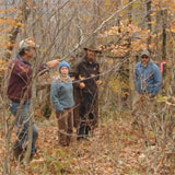 Protesters stand a few yards away from the construction zone — and well within the area they are prohibited from occupying if and when the blasting comes closer to the ridge line — waiting for the sound of high explosives. The names they supplied, all pseudonyms, are Tigdstenpa (left), Mrs. Muskrat, Muskrat, and Fireweed. Photo by Chris Braithwaite.