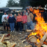 Patterson Park residents stand beside a bonfire being fed with the remains of mobile homes from the park. Photo by Gordon Miller.