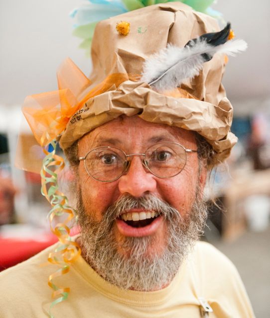 Kevin Dunwoody, showing off one of the hats made in the kids' tent, has been the music director of the New World Festival since it was founded 20 years ago. (Photo by Bob Eddy, courtesy of the Herald of Randolph)