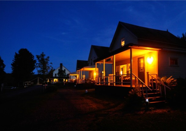 Cabins at Quimby Country glow at night. The main lodge is visible In the background. Photo by Mark Bushnell