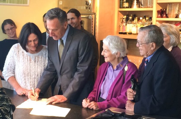 Gov. Peter Shumlin signs the updated physician-assisted suicide bill at a store owned by Katy Lesser, the sister of Maggie Lake, who used a lethal prescription to end a long battle with cancer earlier this year. Photo by Erin Mansfield/VTDigger