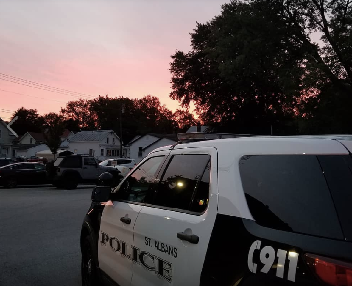 A police car parked in front of a house at sunset.