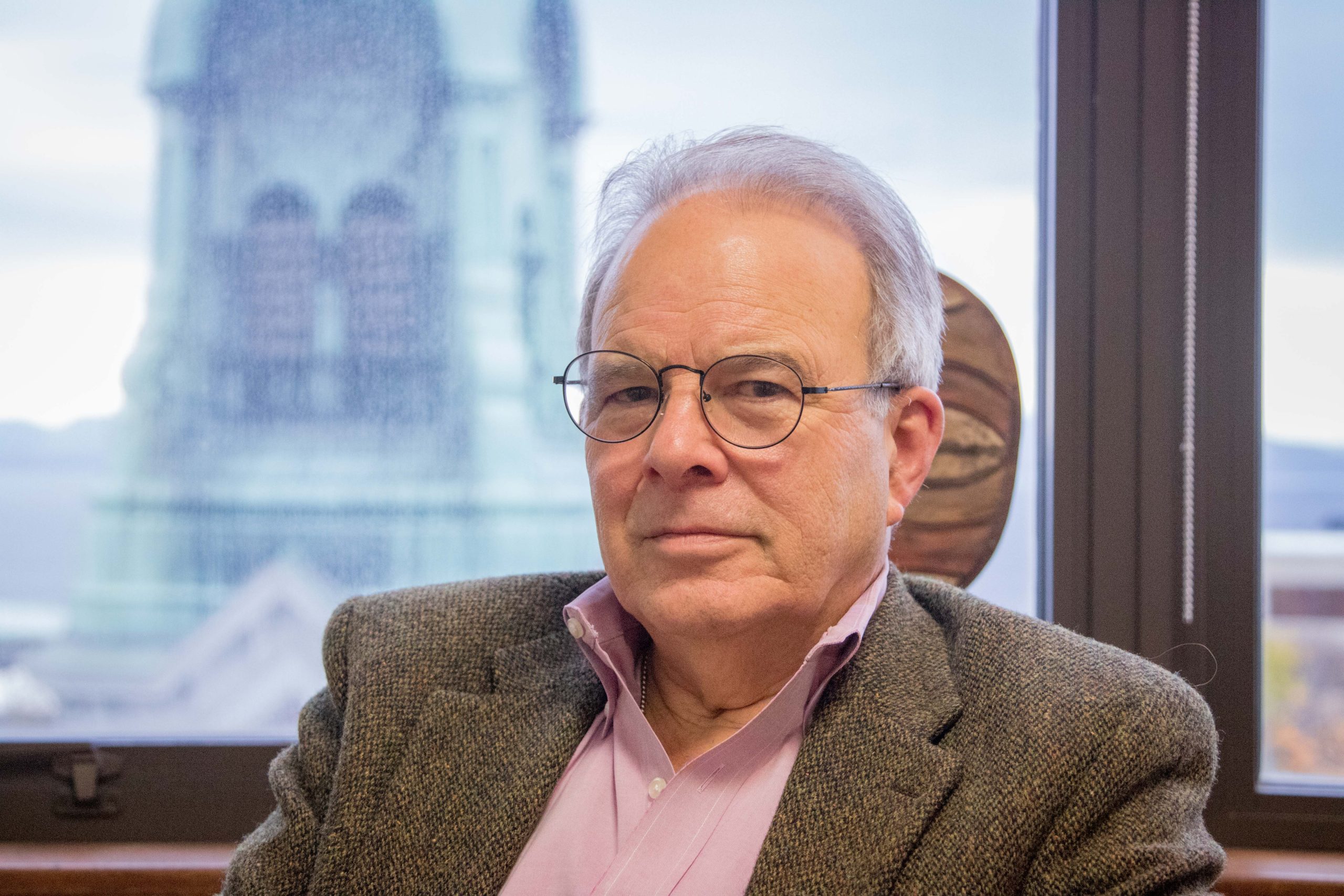 A man in glasses sitting in front of a window.