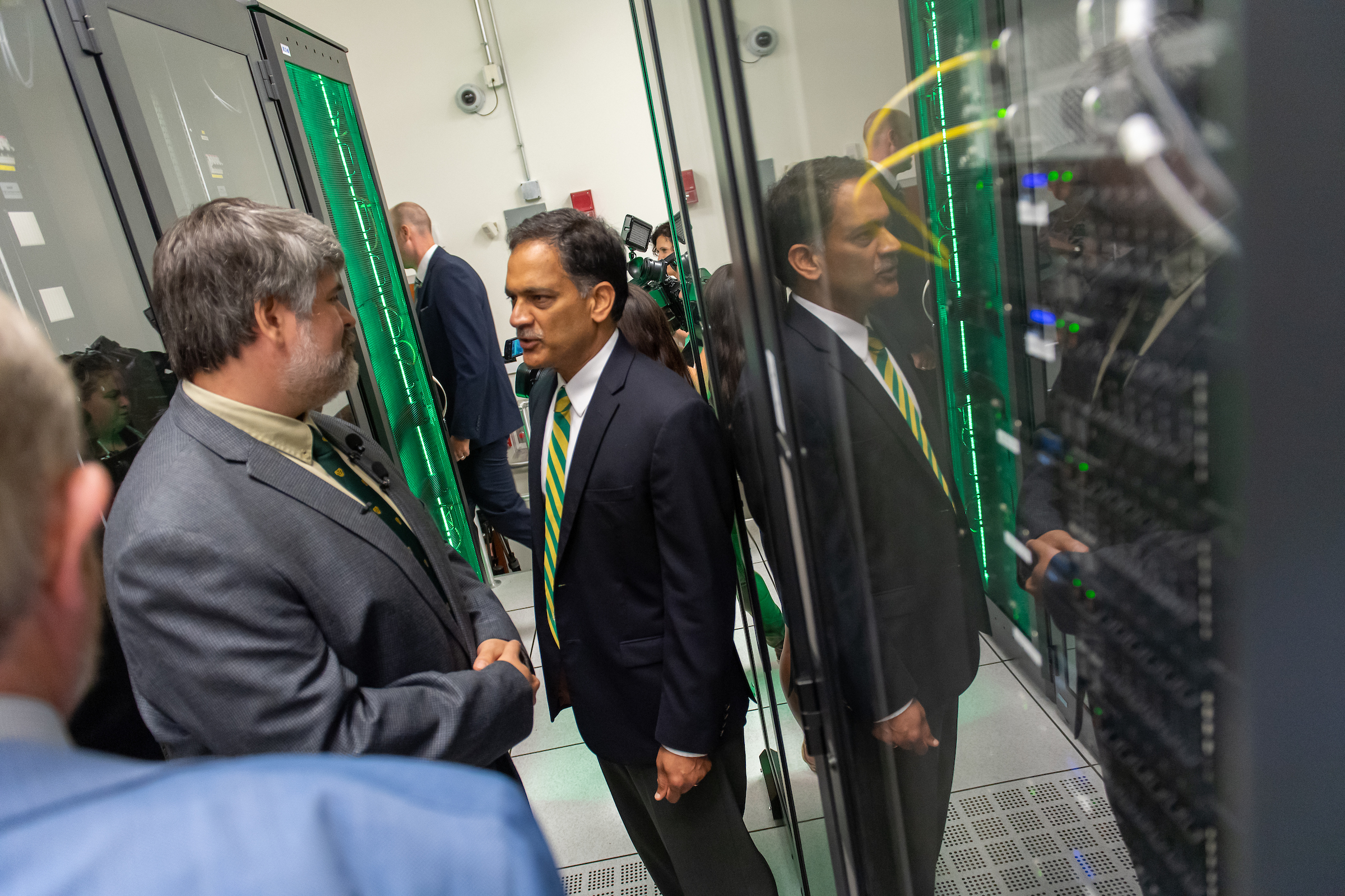UVM president Suresh Garimella (right) speaks with Mike Austin, director of systems architecture at the university, at the unveiling of DeepGreen, 80 high performance graphics processing units that can be seen between the two men. Photo by Sally McCay/Courtesy UVM