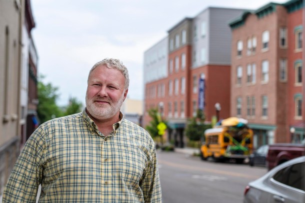 A man in a street lined with buildings.