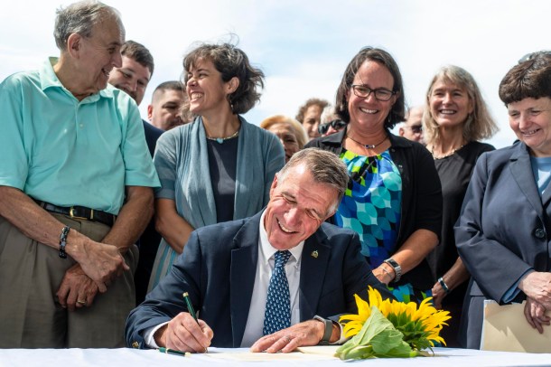 A man signing a document in front of a group of people.