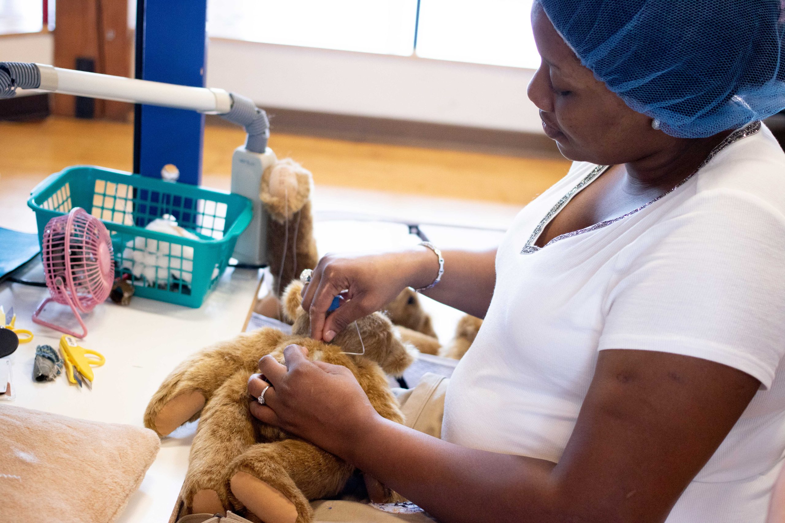 worker sewing teddy bear