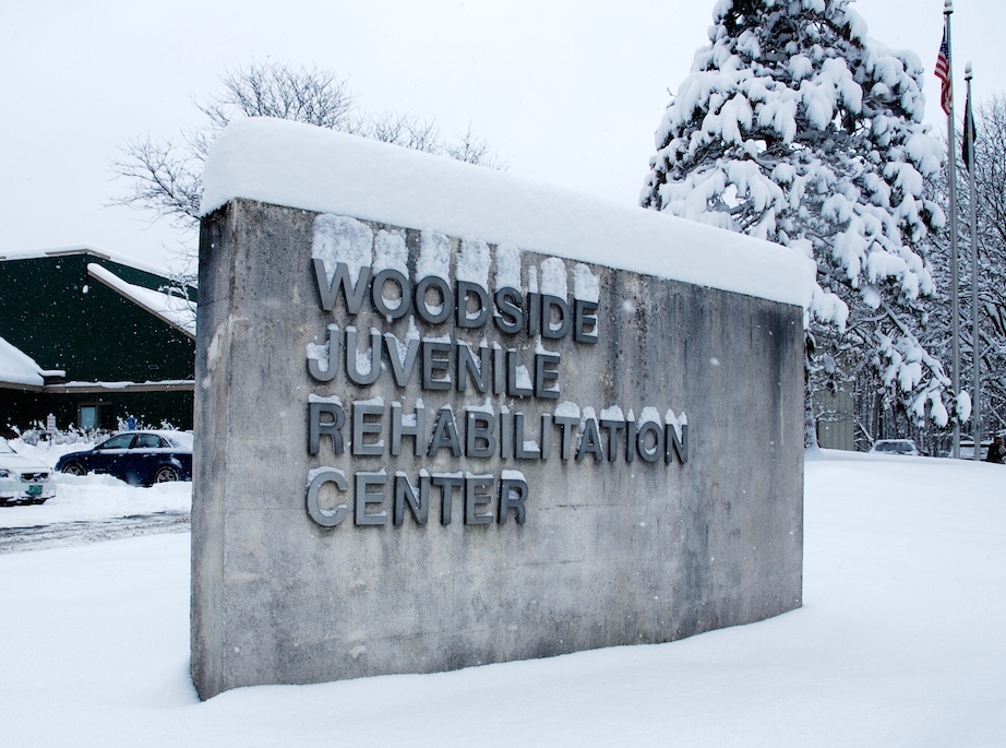 A sign for woodside juvenile rehabilitation center is covered in snow.