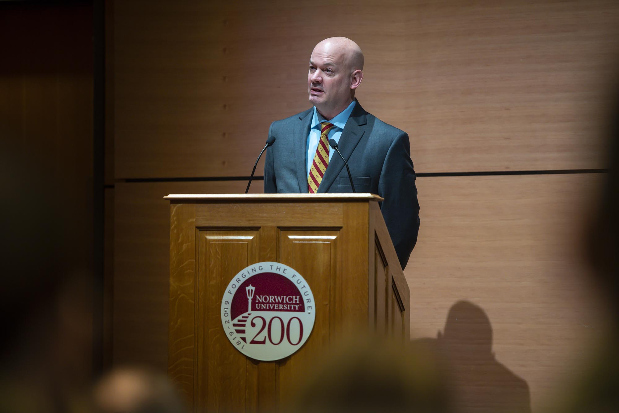 A man in a suit standing at a podium.