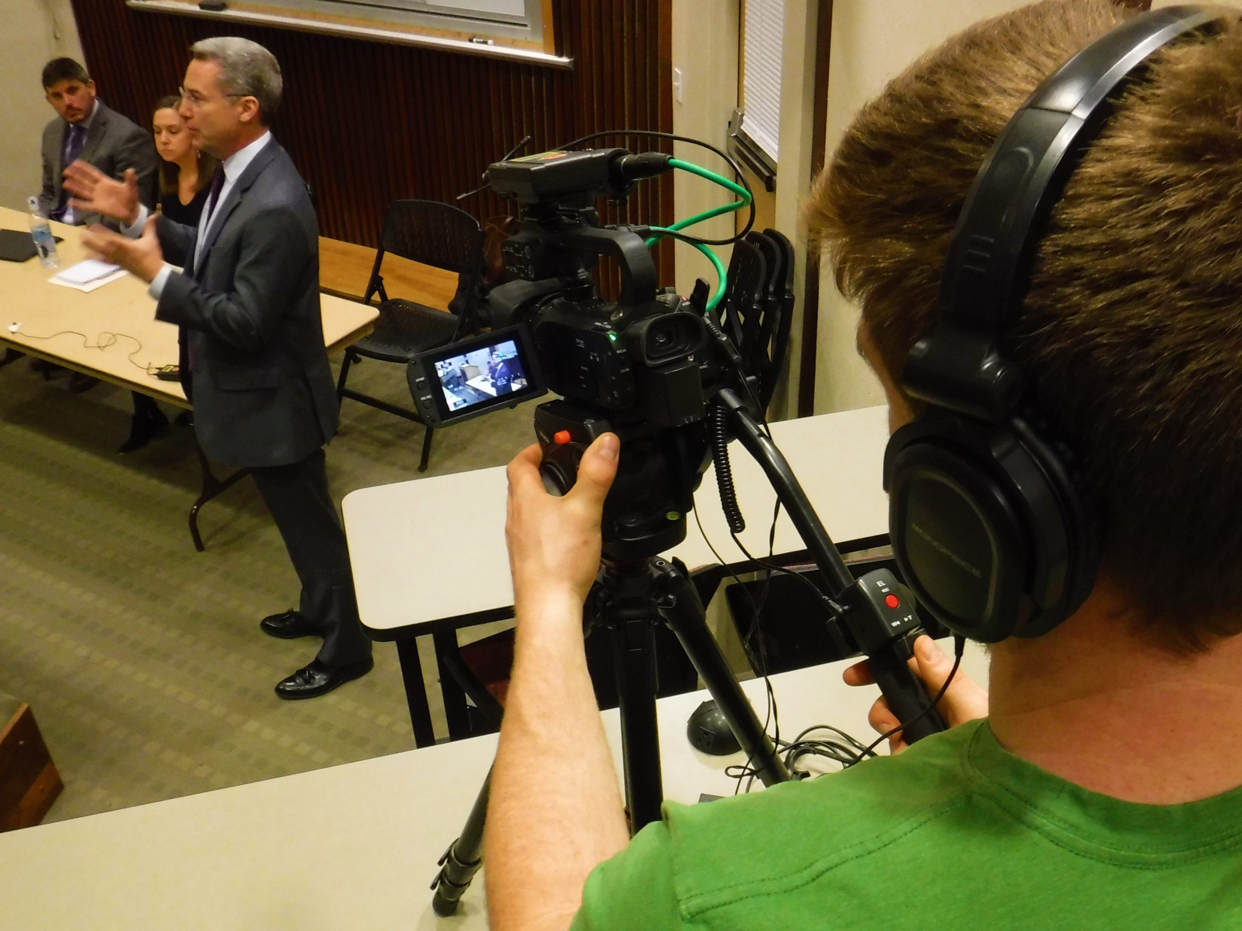 A television camera films Comcast executive Daniel Glanville speaking at a recent Putney public hearing on the proposed sale of Southern Vermont Cable to Comcast. Photo by Kevin O’Connor/VTDigger
