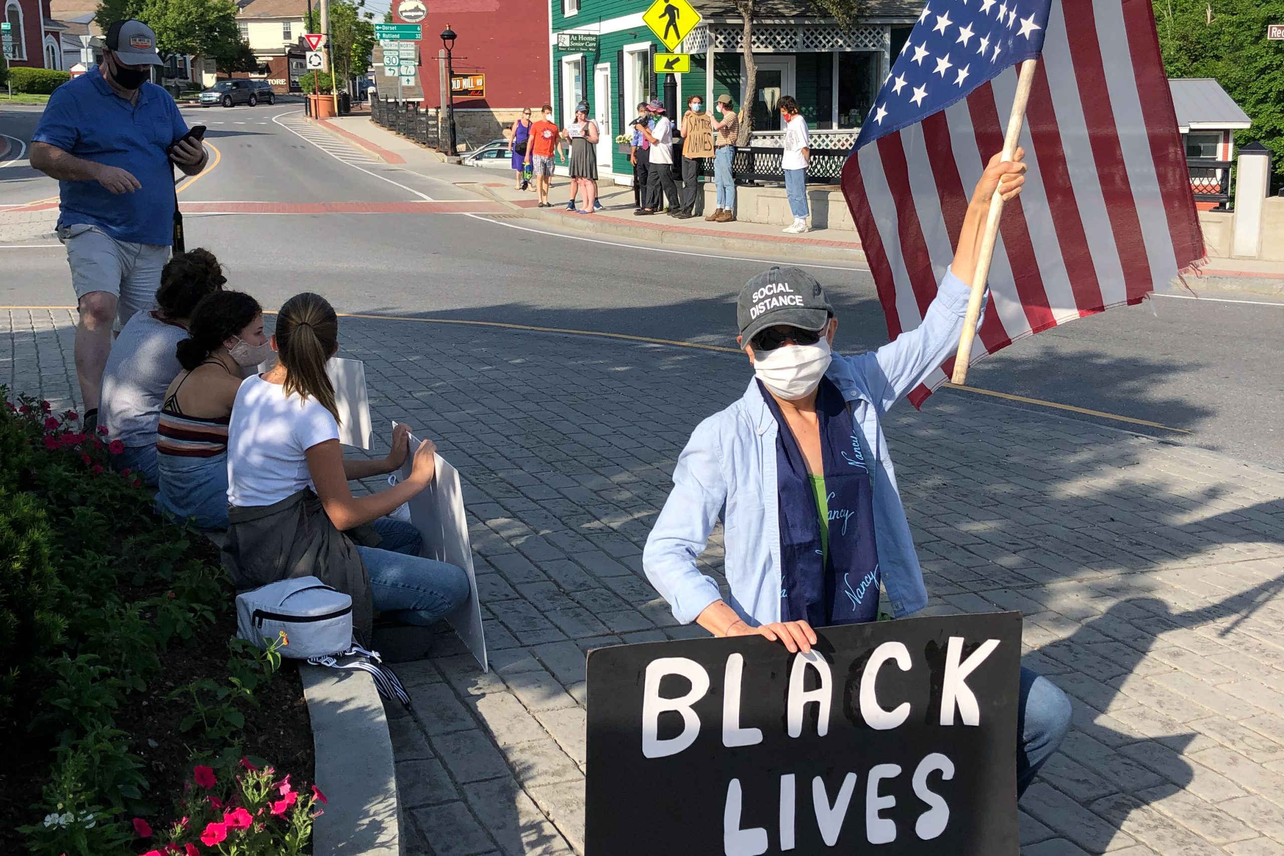 woman holding flag and black lives matter sign