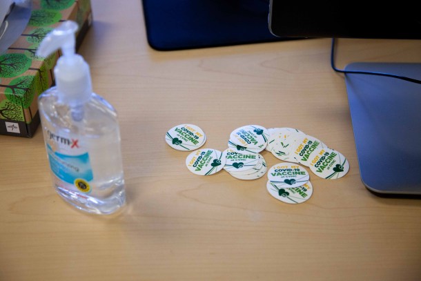 pile of "I Got My Covid-19 Vaccine" stickers and hand sanitizer dispenser