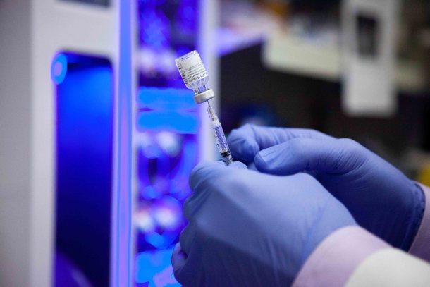 gloved hands holding vial on syringe