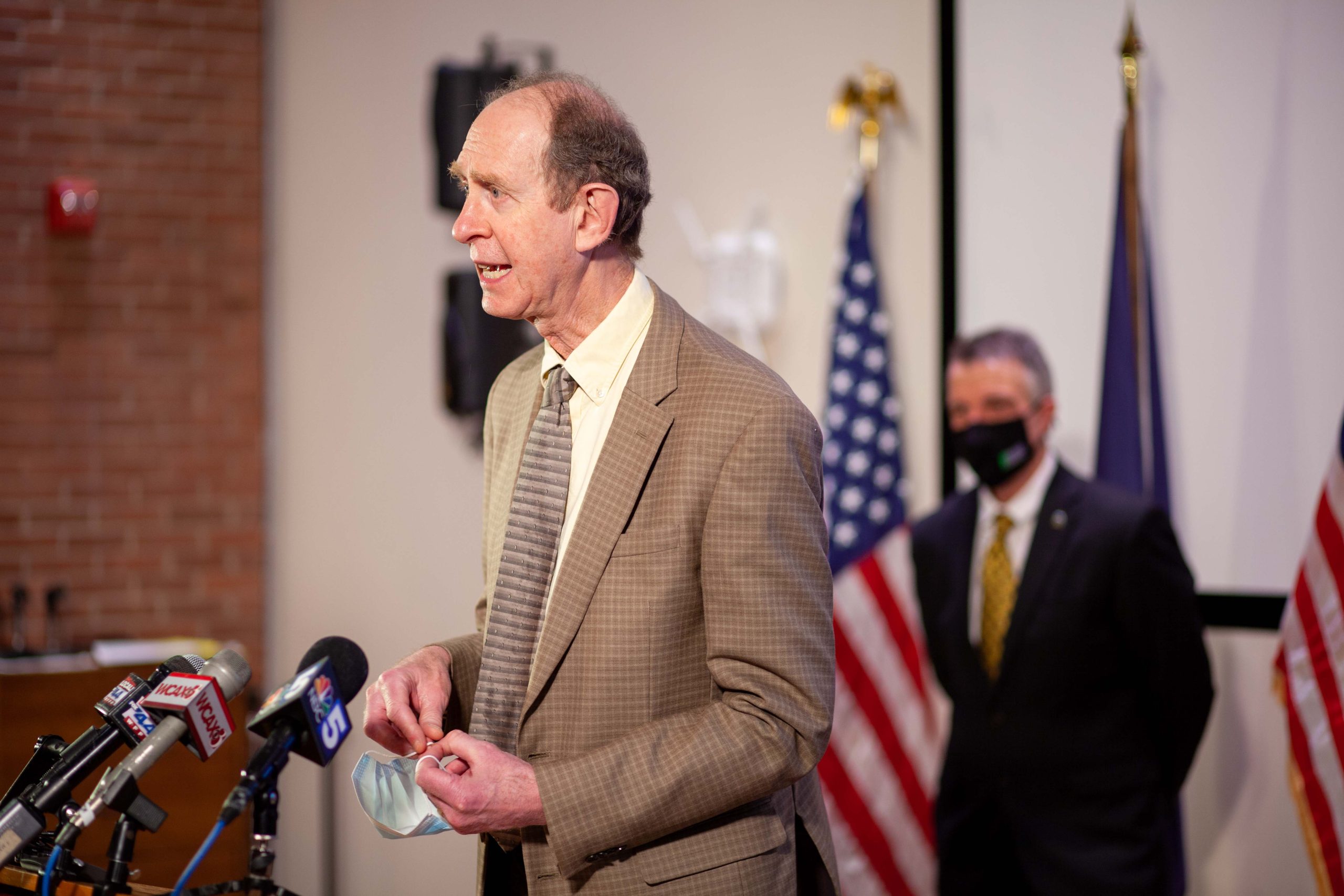 Mark Levine at podium, Phil Scott in background