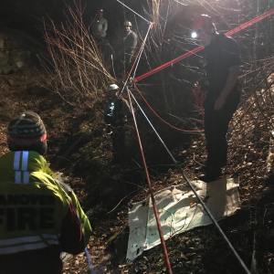 People with ropes and headlamps stand outside in dark