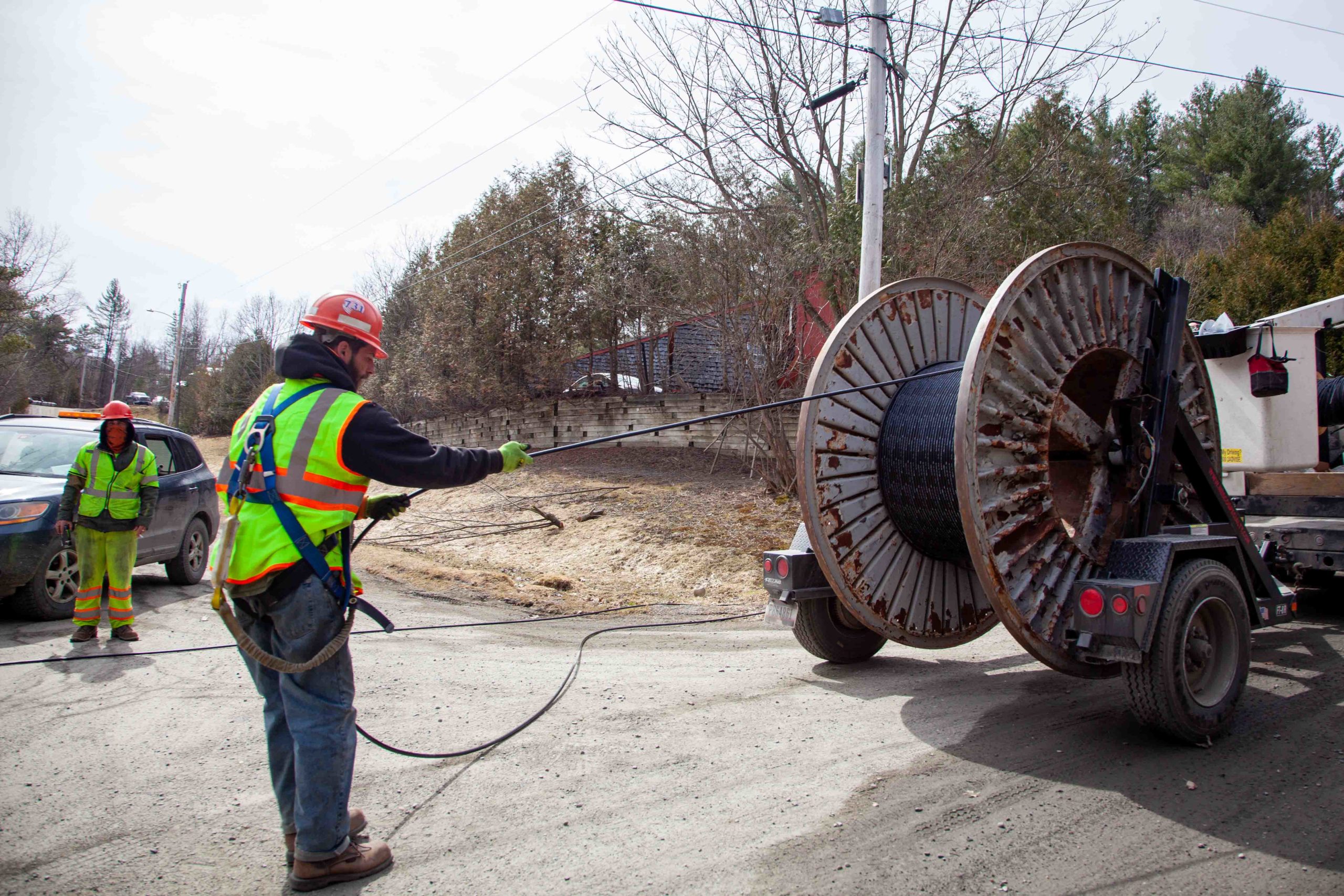 Utility worker unwinds cable from large spool