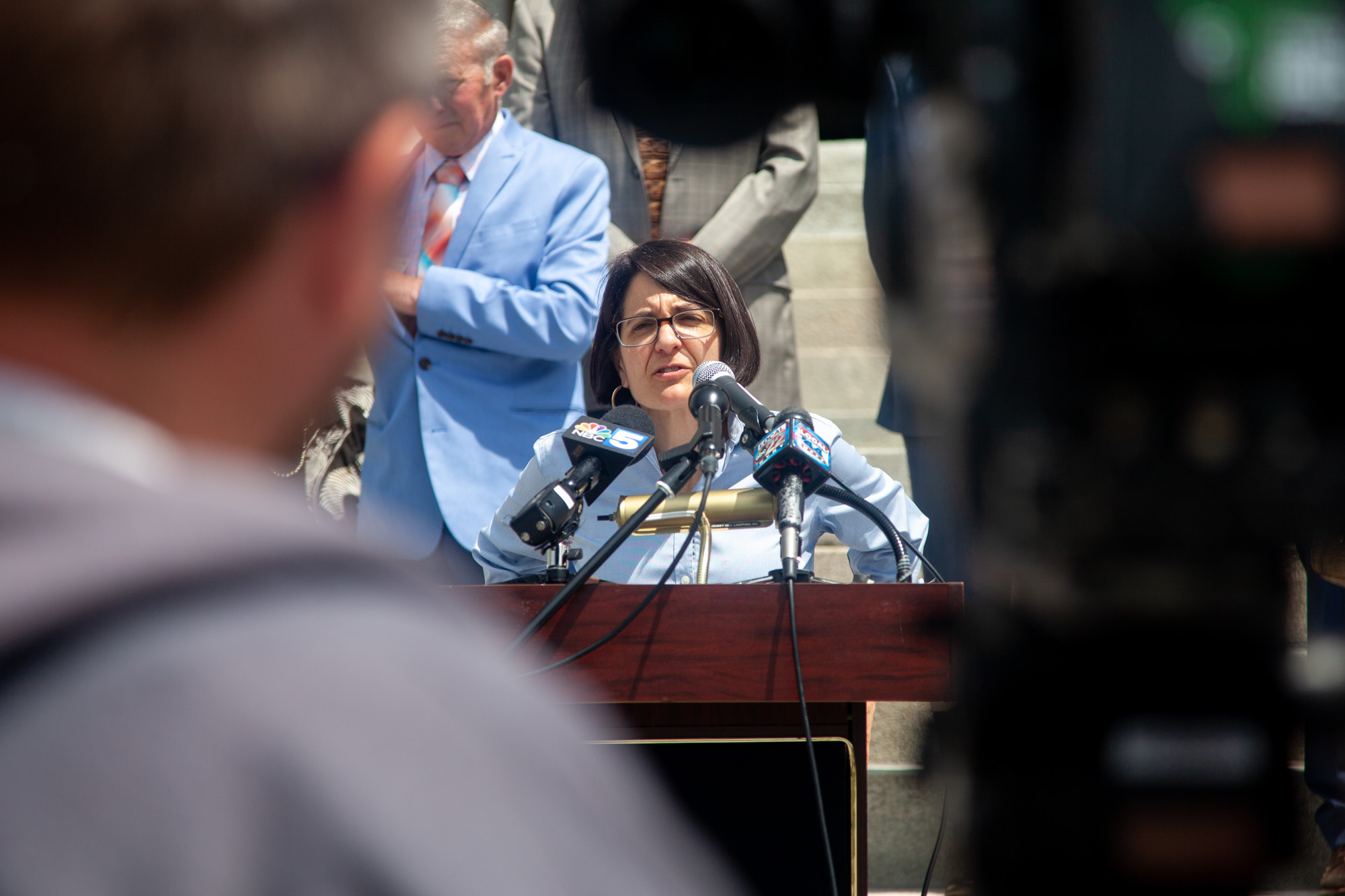 Becca Balint at podium with news camera in foreground