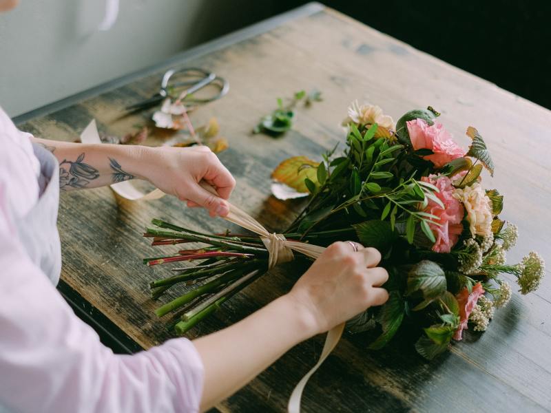 A person ties a bouquet of flowers.