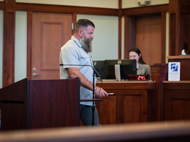 A man standing at a podium in a courtroom.