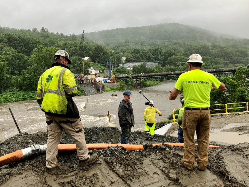 a group of workers standing near a muddy river.