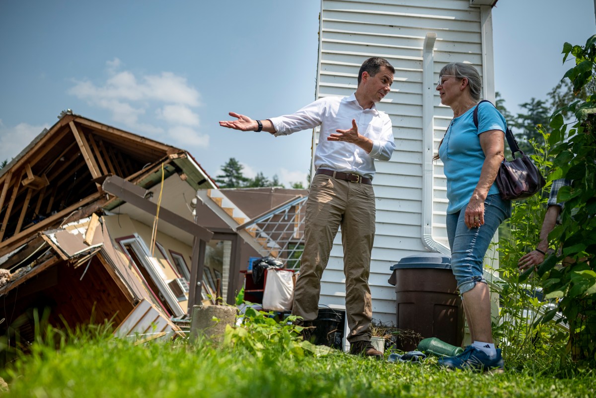 a man and woman standing in front of a damaged house.