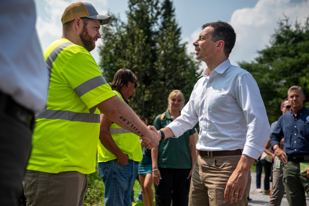 a man in a safety vest shaking hands with another man.