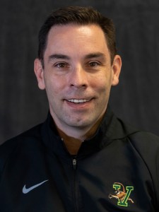 a man in a black jacket smiles for the camera.