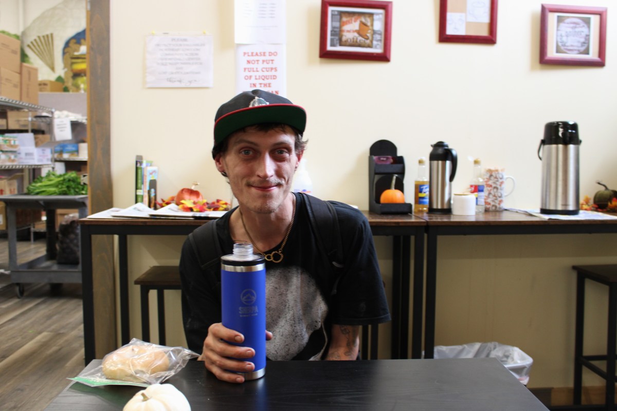 A man sitting at a table with a blue water bottle.