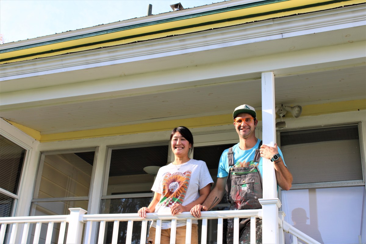 Two people standing on the porch of a house.